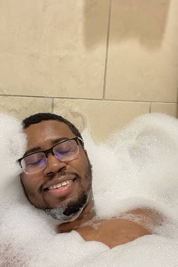 reviewer surrounded by bubbles after using Dr. Teal's lavender bath salt 