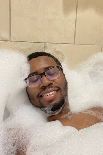 reviewer surrounded by bubbles after using Dr. Teal's lavender bath salt 