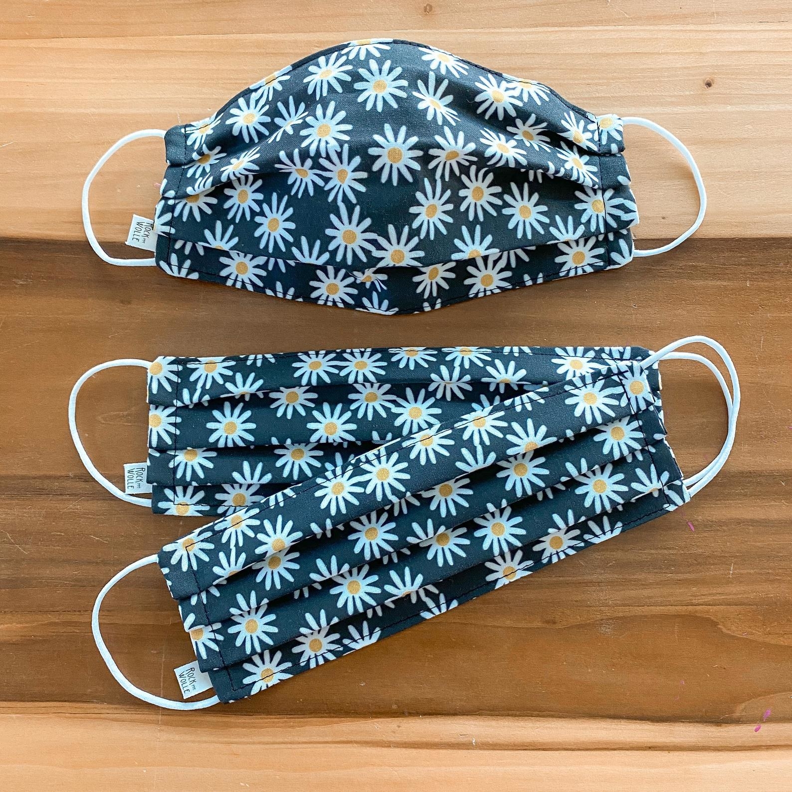 two gray non medical face masks with a white daisy print all over