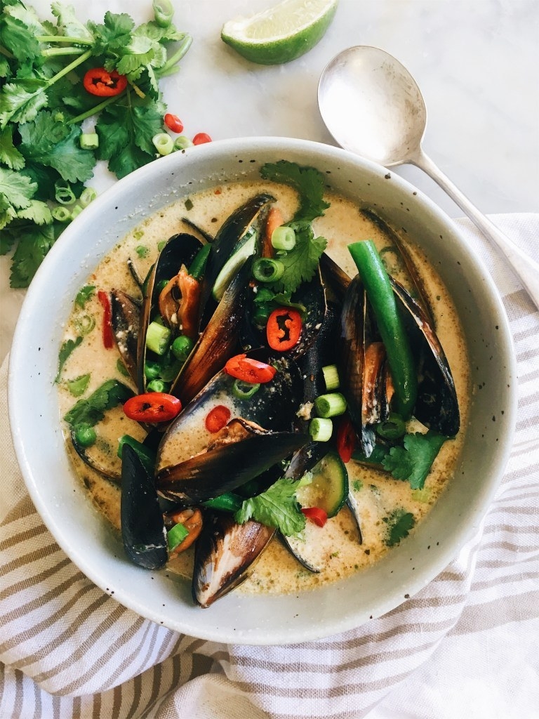 A bowl of mussels in coconut broth with chili and scallions.