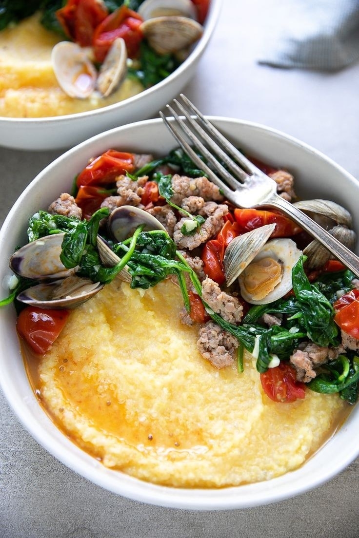 A bowl of polenta with clams and sausages.