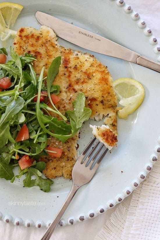 A piece of fish Milanese topped with arugula.
