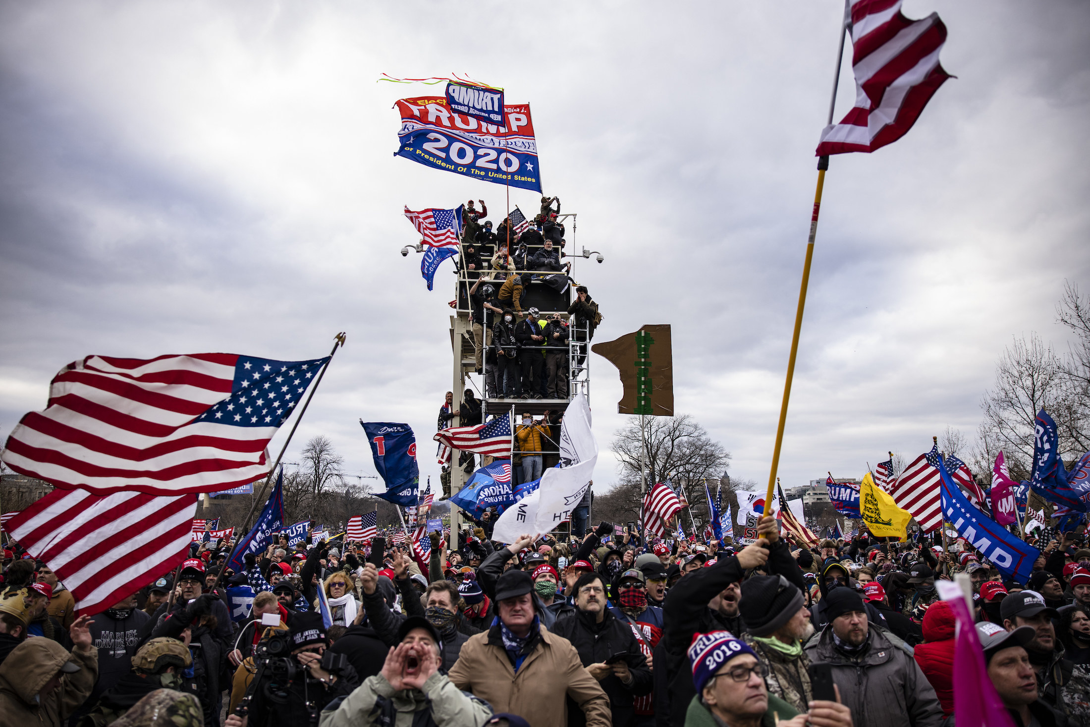 Pro-Trump supporters stand on a piece of scaffolding and wave Trump flags 