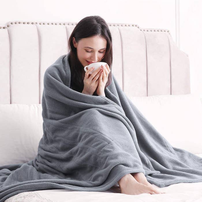 person wrapped in blanket holding a mug 