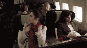 person looking around and then reclining her seat on an airplane
