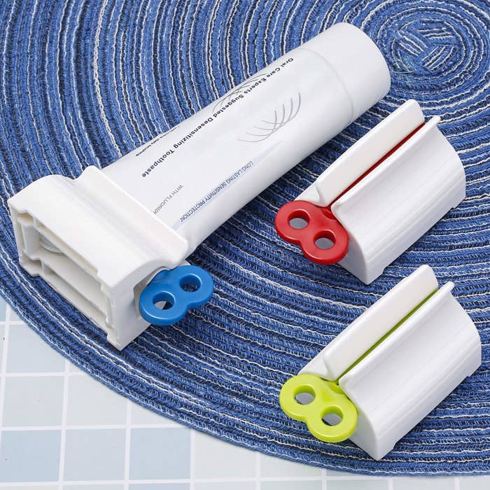 A set of three toothpaste squeezers on a blue mat
