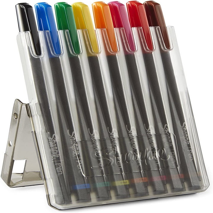 The black, blue, green, yellow, orange, pink, red, and brown pens in their case that doubles as a stand