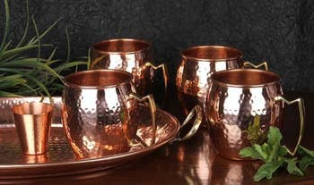 the four copper mugs with the copper shot glass next to them