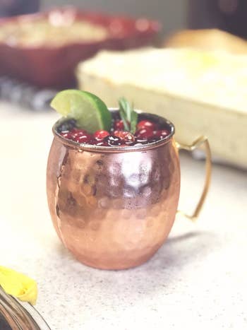 reviewer pic of one copper mug with a drink with cranberries and limes in it