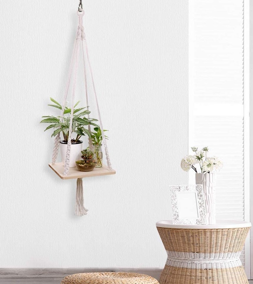 A hanging macrame shelf with a wooden surface  