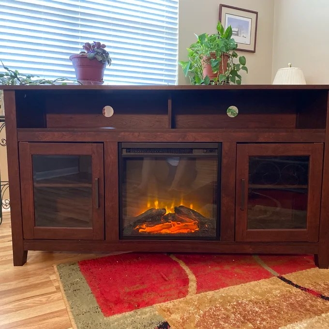 The TV stand photographed up close with fireplace burning