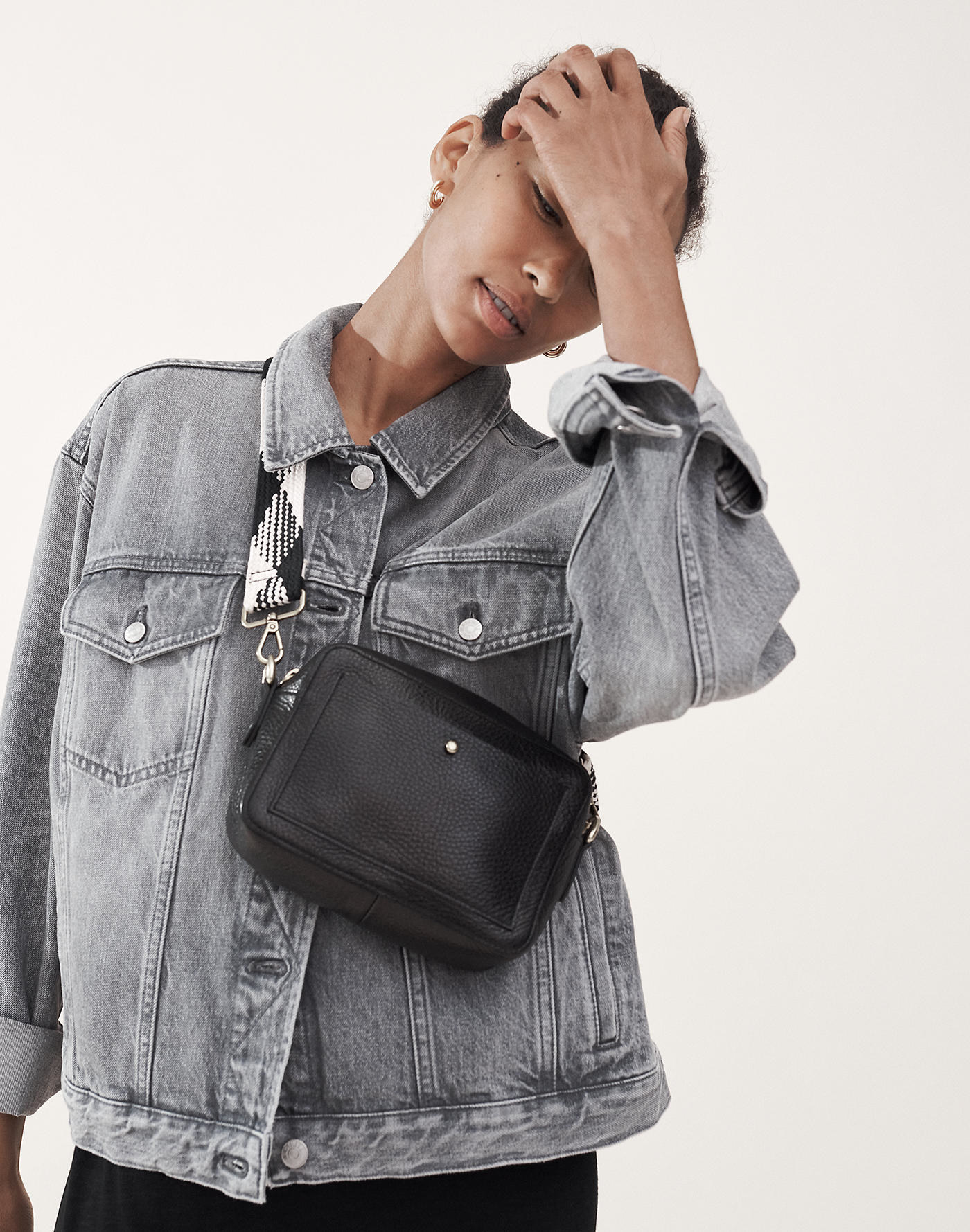 model with the rectangle bag with front pocket across their body with black and white patterned strap