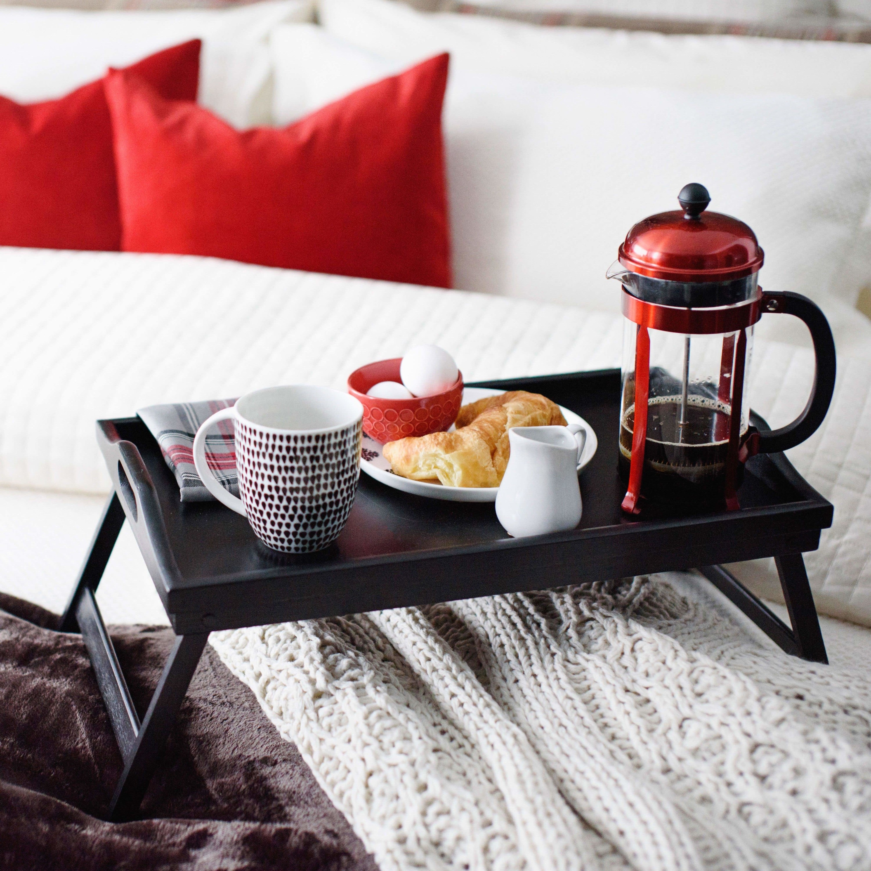 the tray on a bed with coffee and some breakfast foods