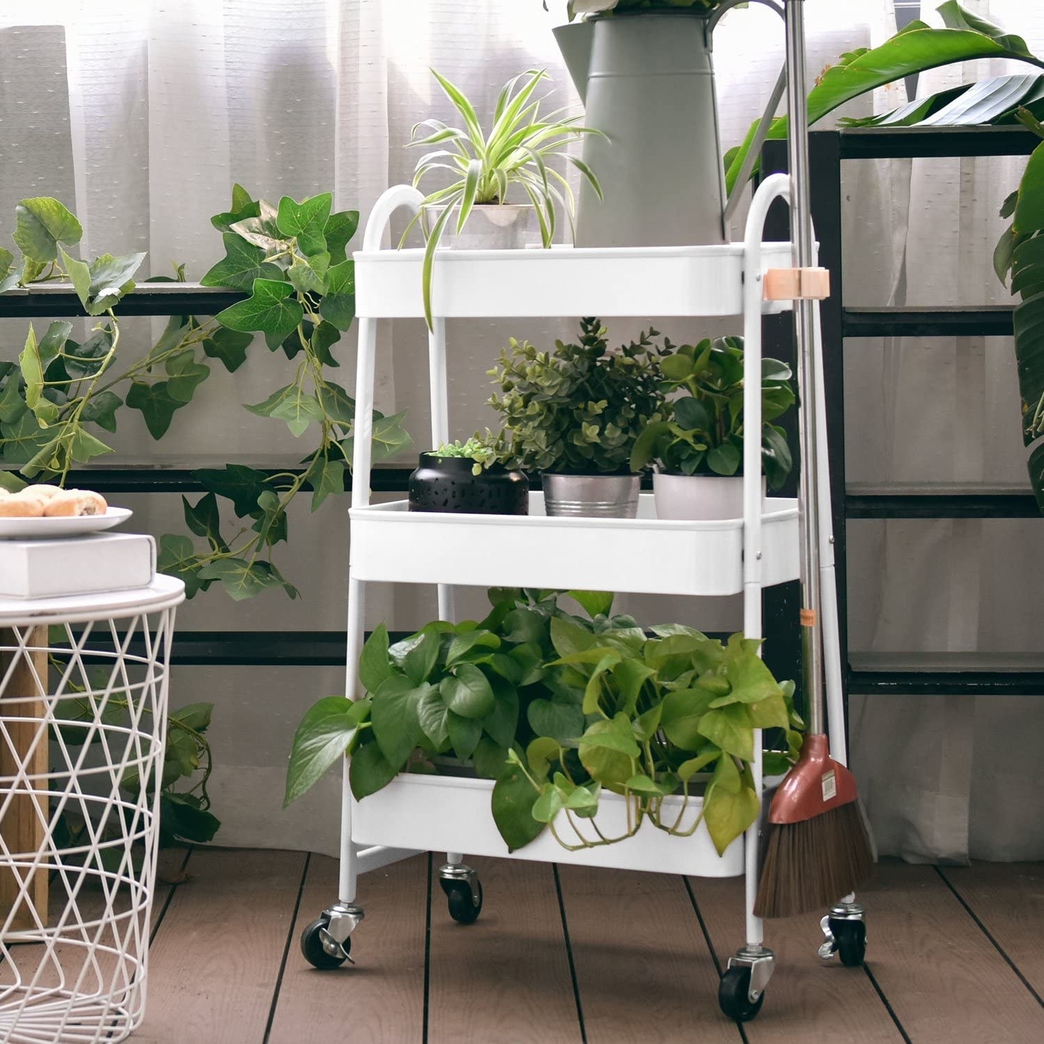 A utility cart with three shelves of plants on it 
