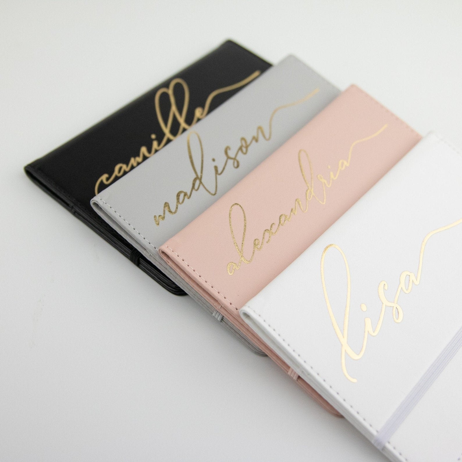 the passport holders in black, gray, pink, and white in gold font.