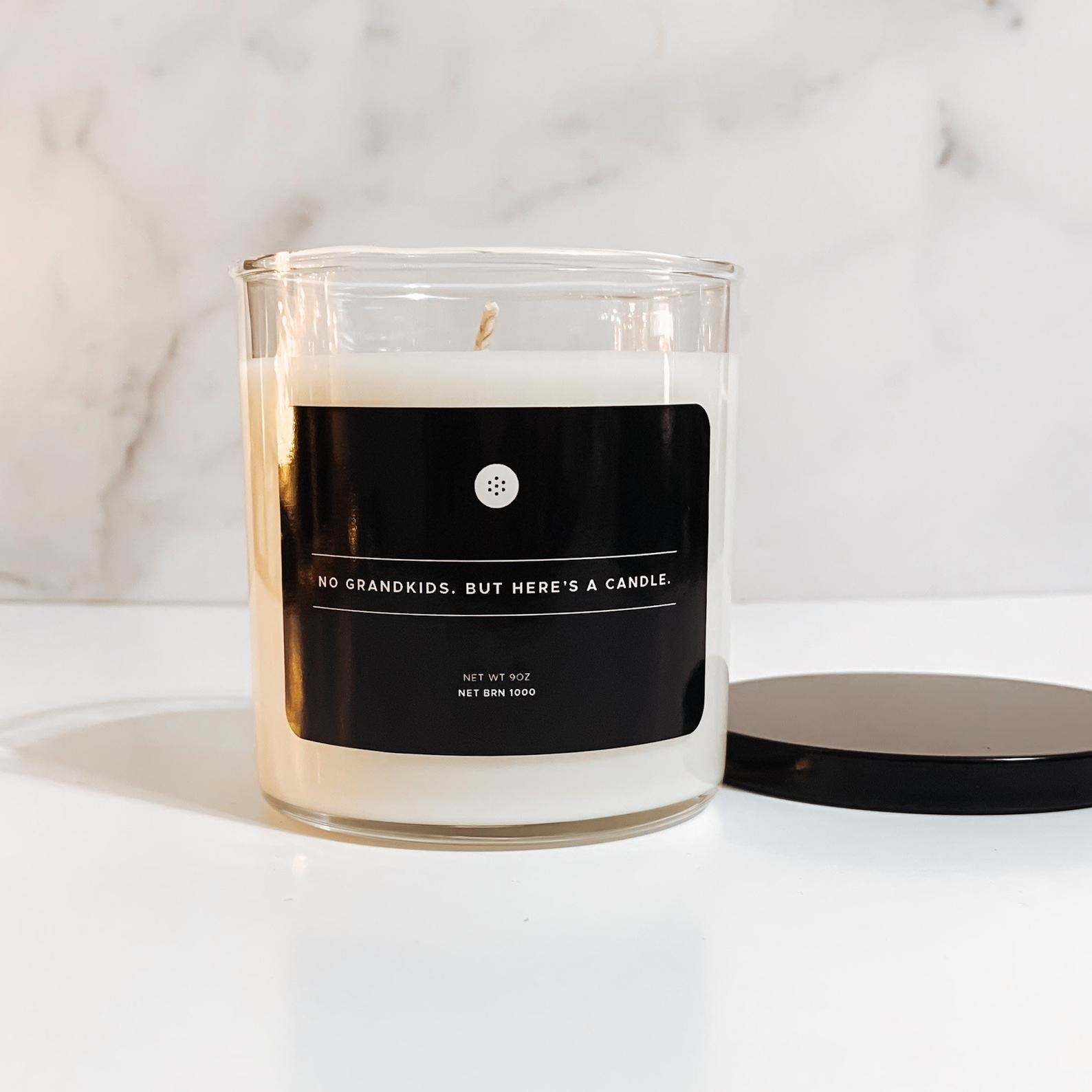a white candle with a black label that says &quot;no grandkids, but here&#x27;s a candle&quot;