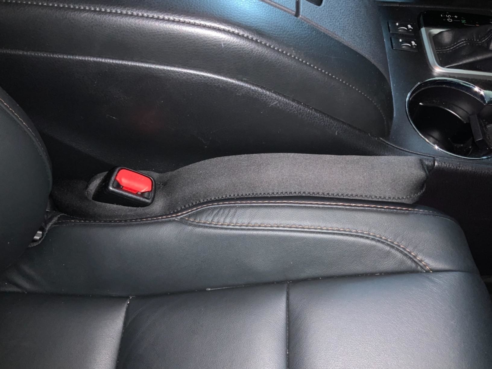 A reviewer photo of a car with the Drop Stop care seat gap filler installed on the left side of the passenger seat 