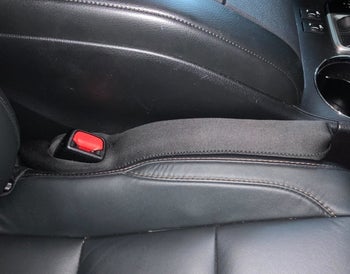 A reviewer photo of a car with the Drop Stop care seat gap filler installed on the left side of the passenger seat 