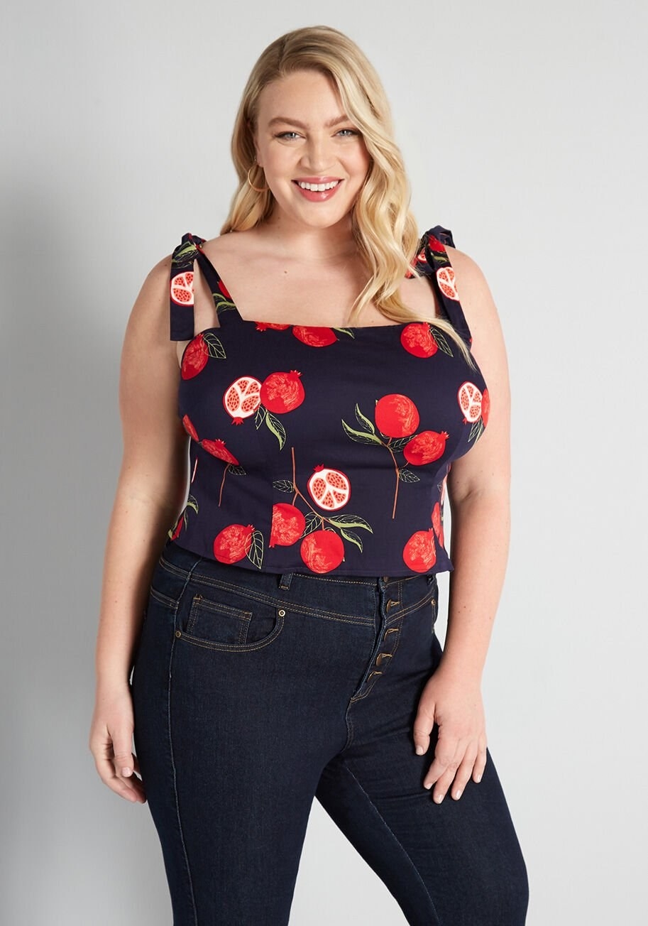 Model wearing a navy blue tank top with bright red pomegranates on it