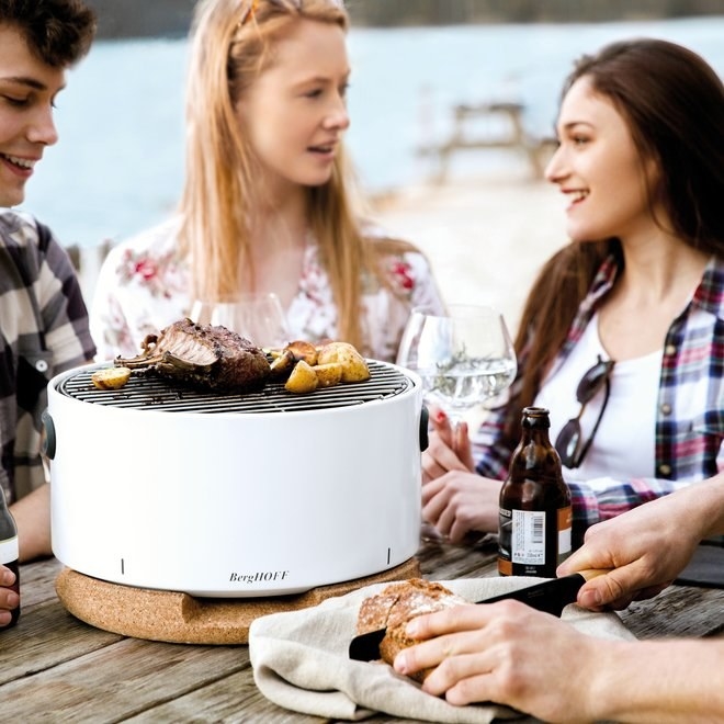 People grilling meat and potatoes on the white barbecue