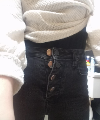 reviewer wearing jeans with multiple buttons 