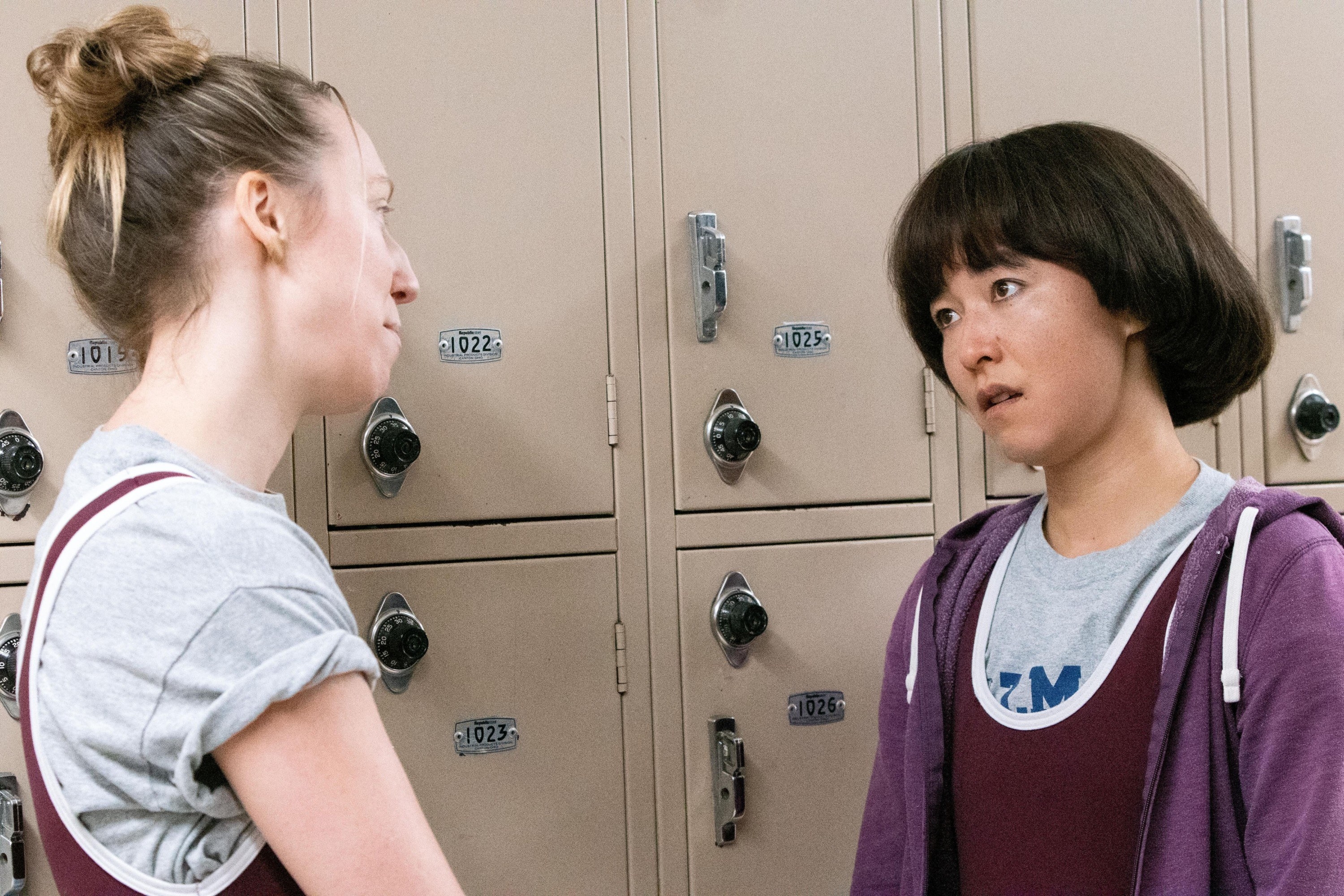 Anna Konkle and Maya Erskine talking by a set of lockers while wearing wrestling jerseys in the PEN15 episode &quot;Wrestle&quot;