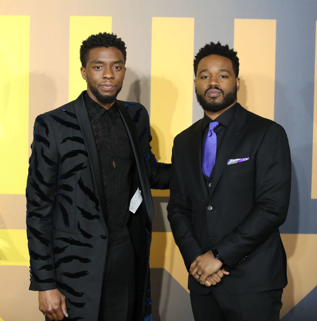 Ryan Coogler and Chadwick Boseman, both in dark suits, posing on a red carpet