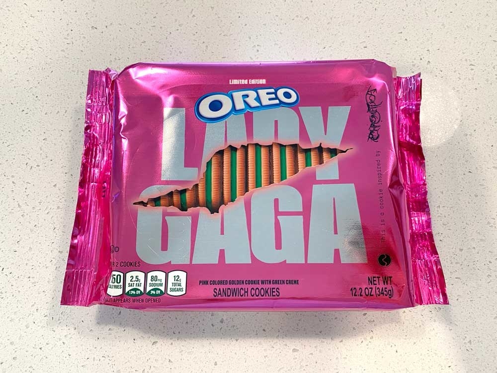 A metallic pink Oreo package with &quot;Lady Gaga&quot; written on it and a fake torn image of the package revealing the pink oreo cookies with green filling