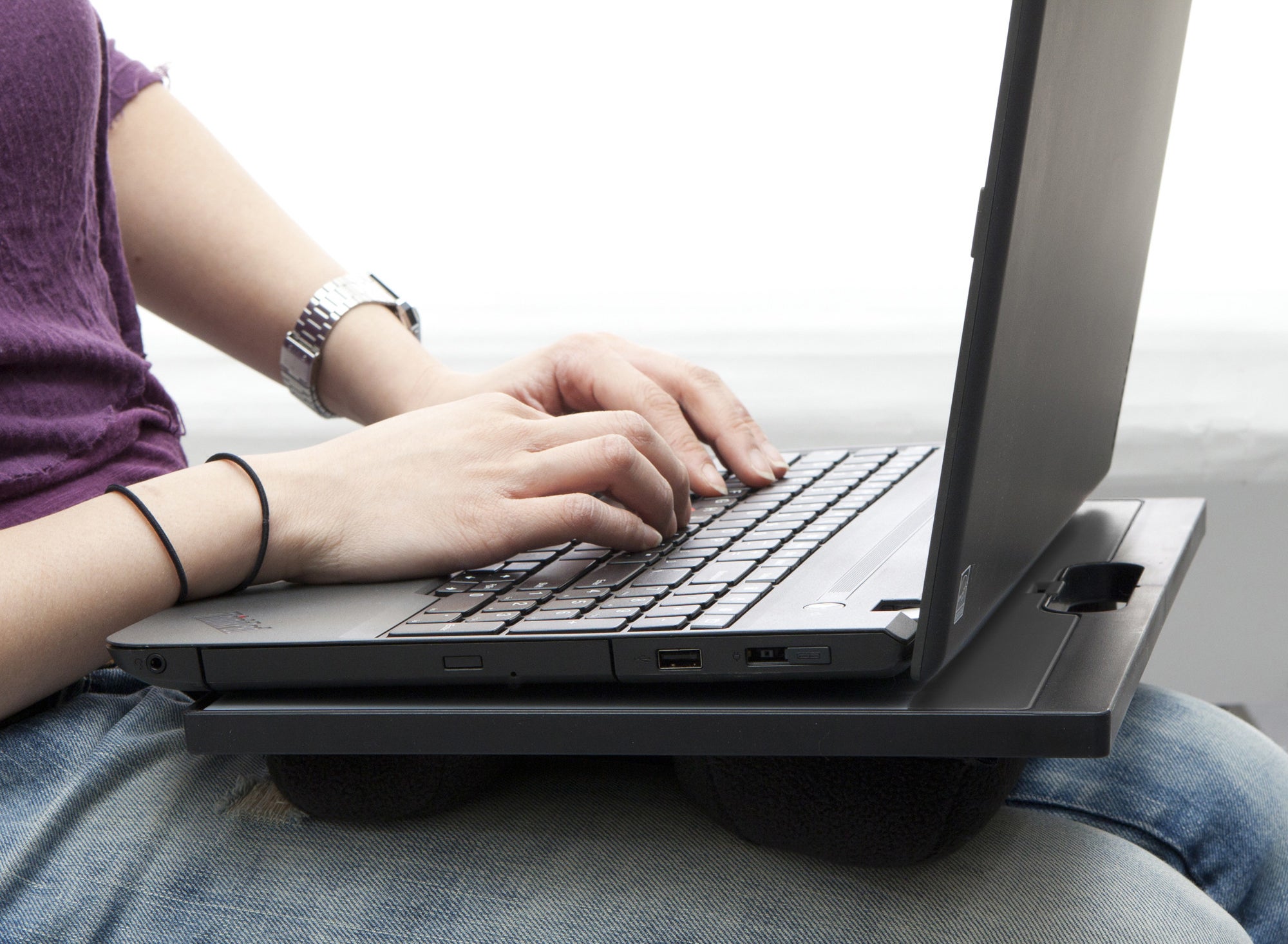 person using a lap desk with a black laptop on top