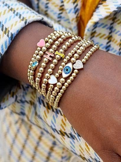a model wearing a stack of gold beaded bracelets