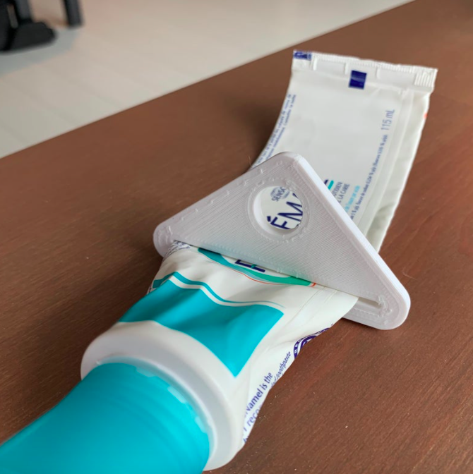 A triangle-shaped tube squeezer on a tube of toothpaste