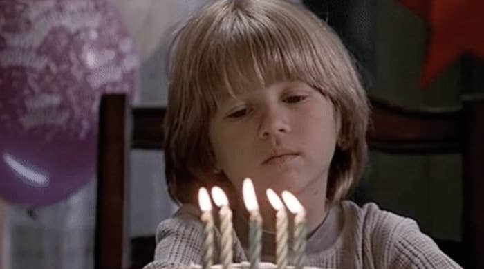 Kid looking sad at a birthday candle.