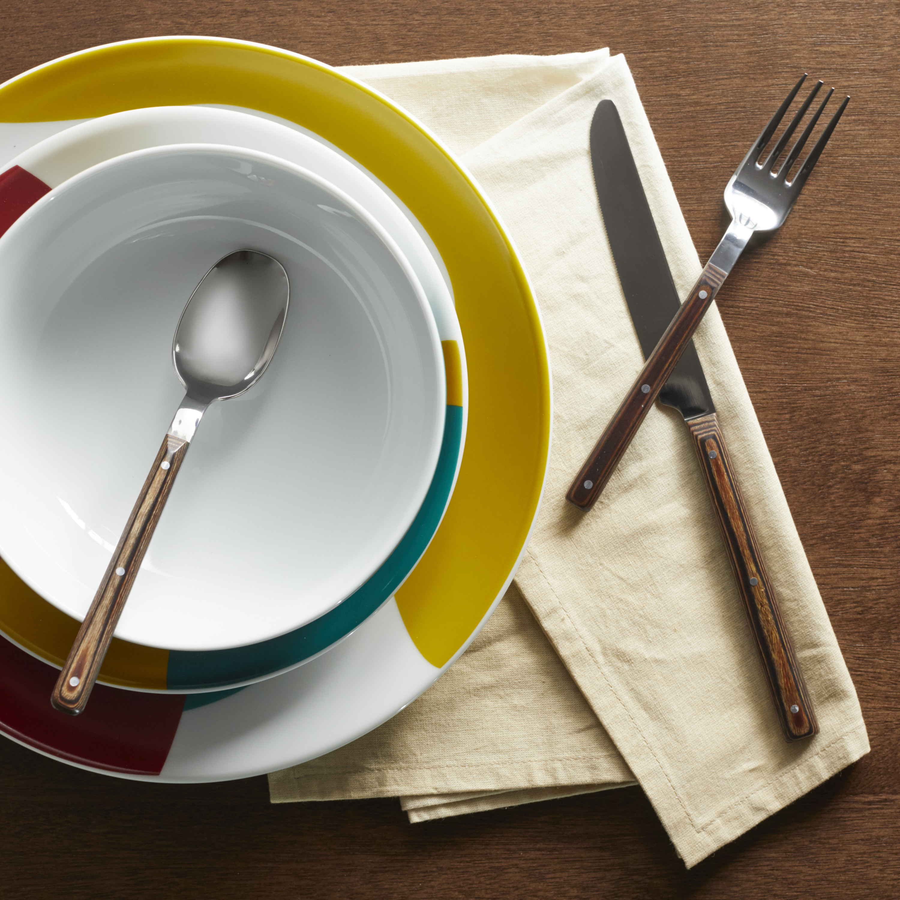 The flatware on a brightly colored dinnerware set