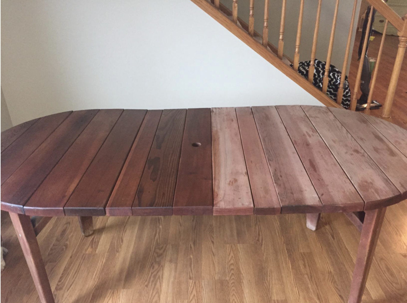 a reviewer photo of a table with the before on the right side of the photo and the after on the left showing a significant difference in the shade and shine of the wood