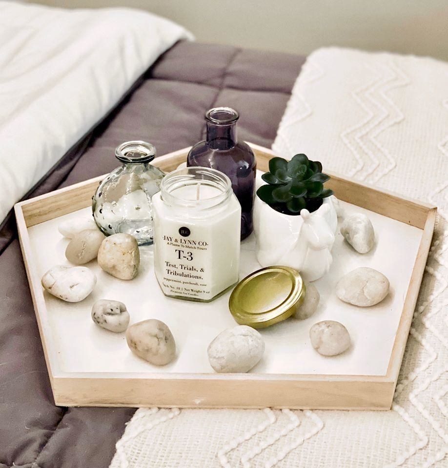 bed with a tray on it containing a candle plus a succulent and rocks