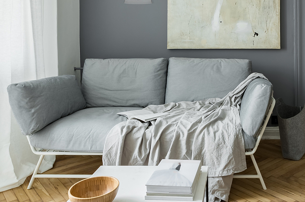 A wall light hung on a wall next to a painting and over a couch