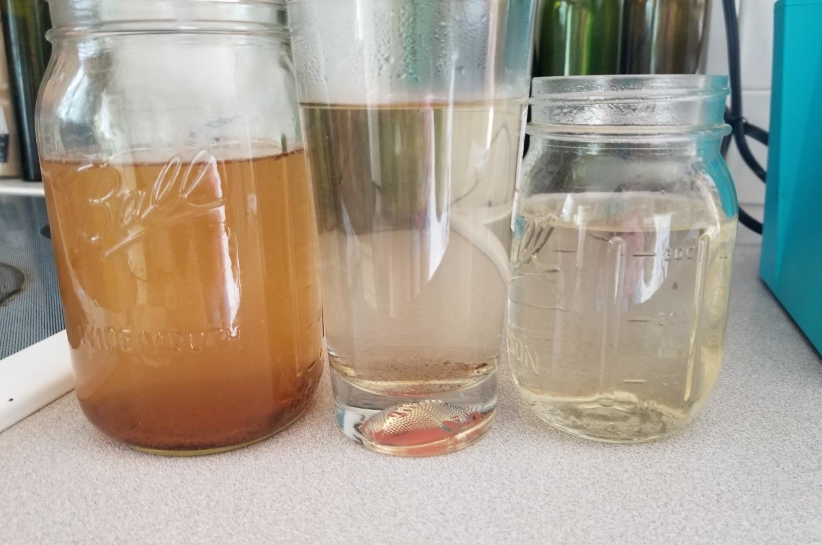 A glass on the left filled with brown water, a glass in the middle filled with cloudy water, and a glass on the right filled with clean water 