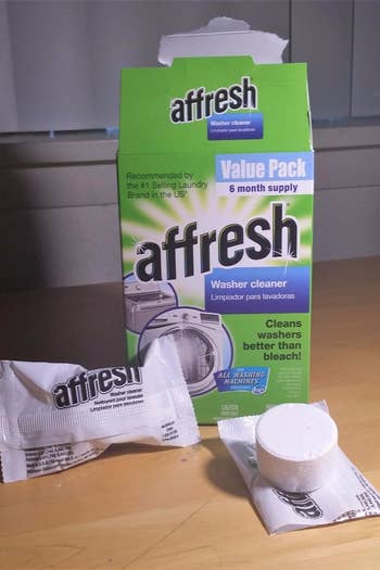 The Affresh Washing Machine Cleaner Tablets packaging next to an open tablet 