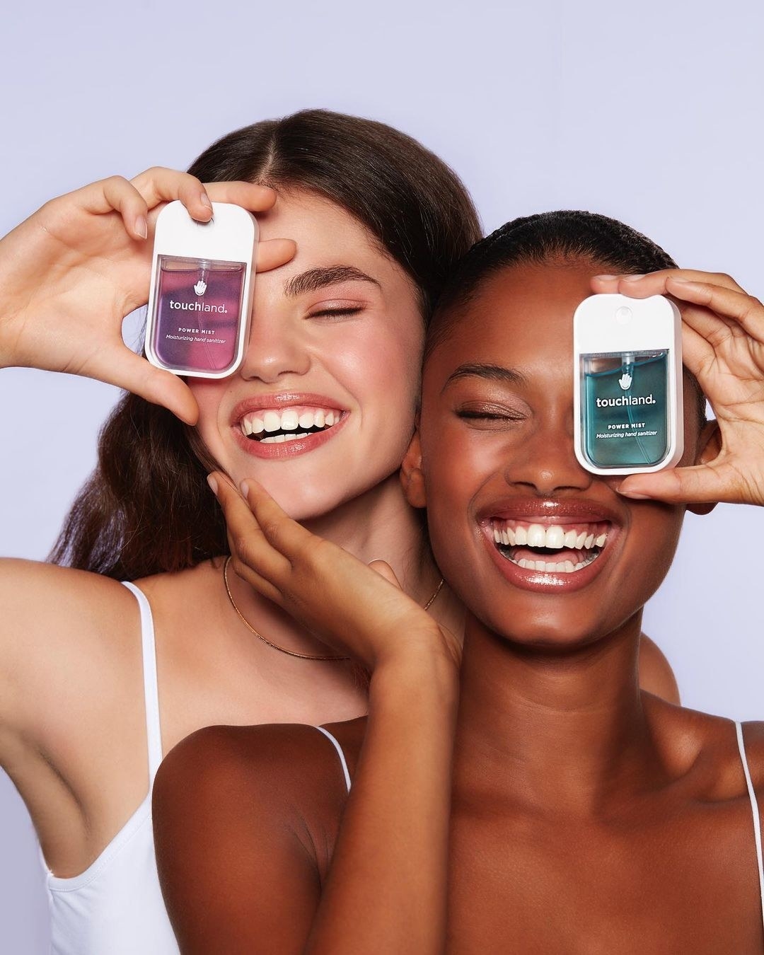 A pair of smiling models holding up bottles of the hand sanitizer