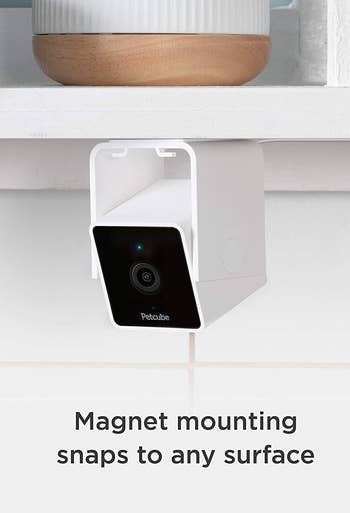 A small camera mounted to the bottom of a kitchen shelf 