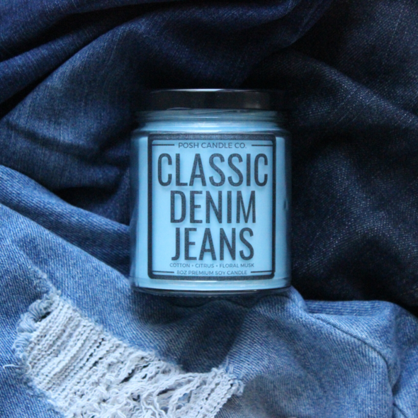 blue candle in a jar that says &quot;Classic Denim Jeans&quot; on a pile of jeans