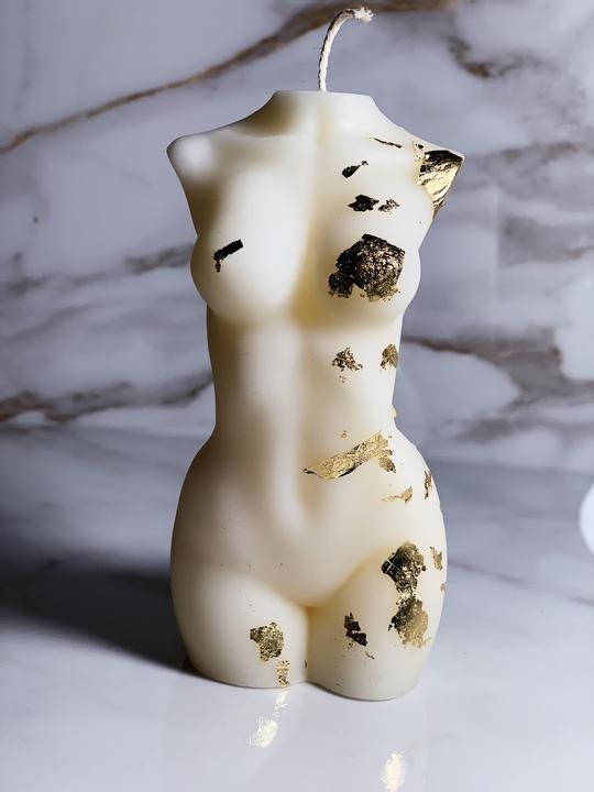 white female form torso candle with bits of gold leaf on it