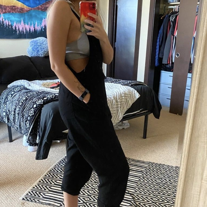 reviewer wearing the jumpsuit with a gray bralette 