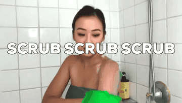 Woman scrubbing her suds-covered arms with a thick, bright green Korean washcloth