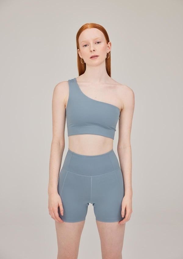 model in light blue off shoulder sports bra with matching bike shorts