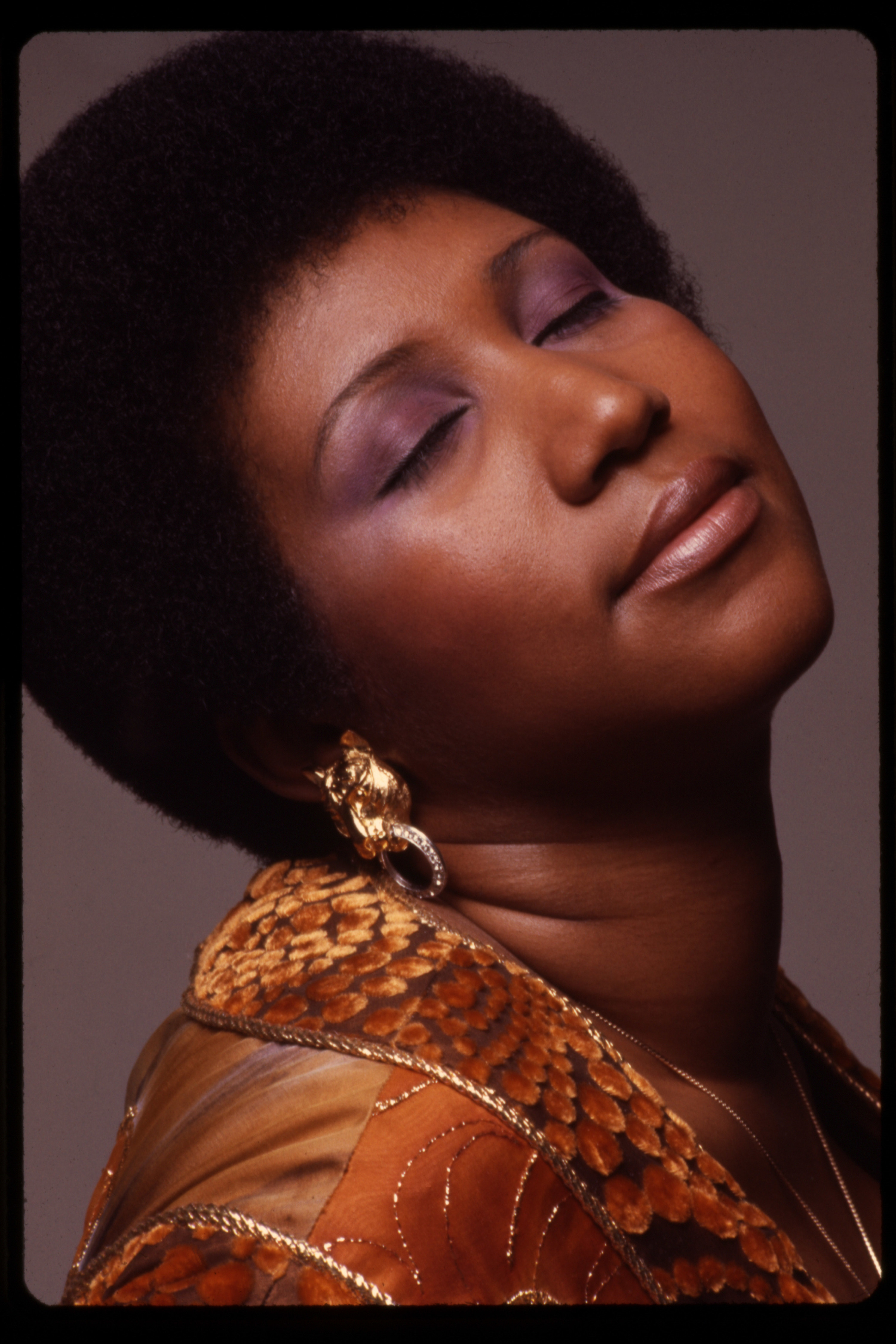 A close-up portrait of Aretha Franklin with her head tilted back 