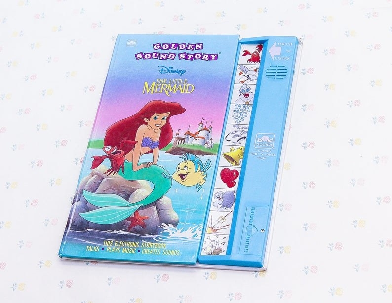 The Little Mermaid sitting on a rock with Sebastian and Flounder on the cover of the book