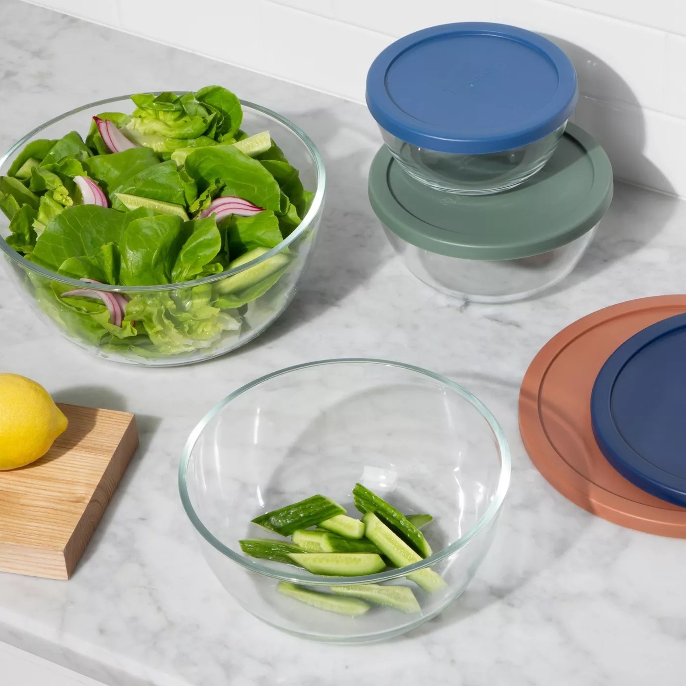 the glass bowls on a counter with veggies inside 