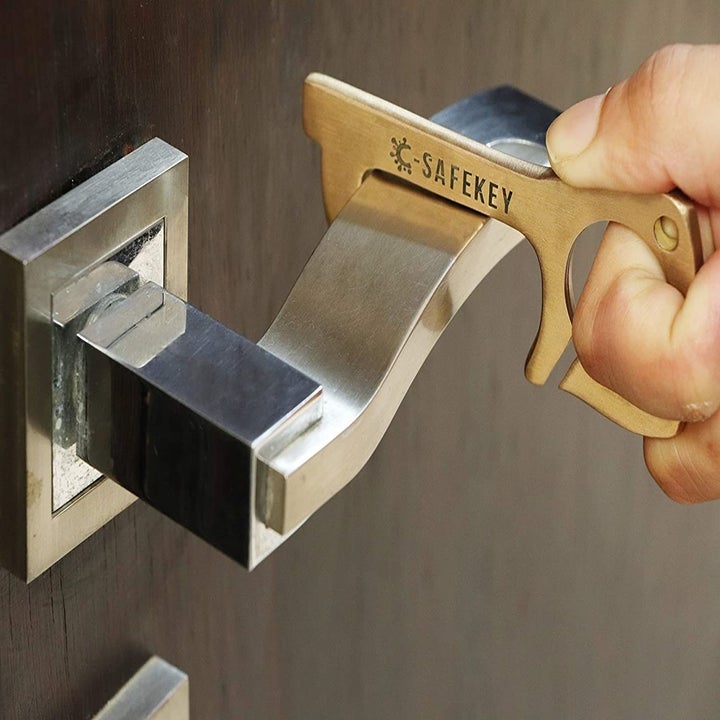 A person using the no-touch tool to open a door.