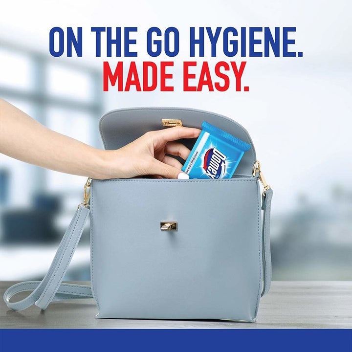 A person fitting the packet of wipes in their handbag.